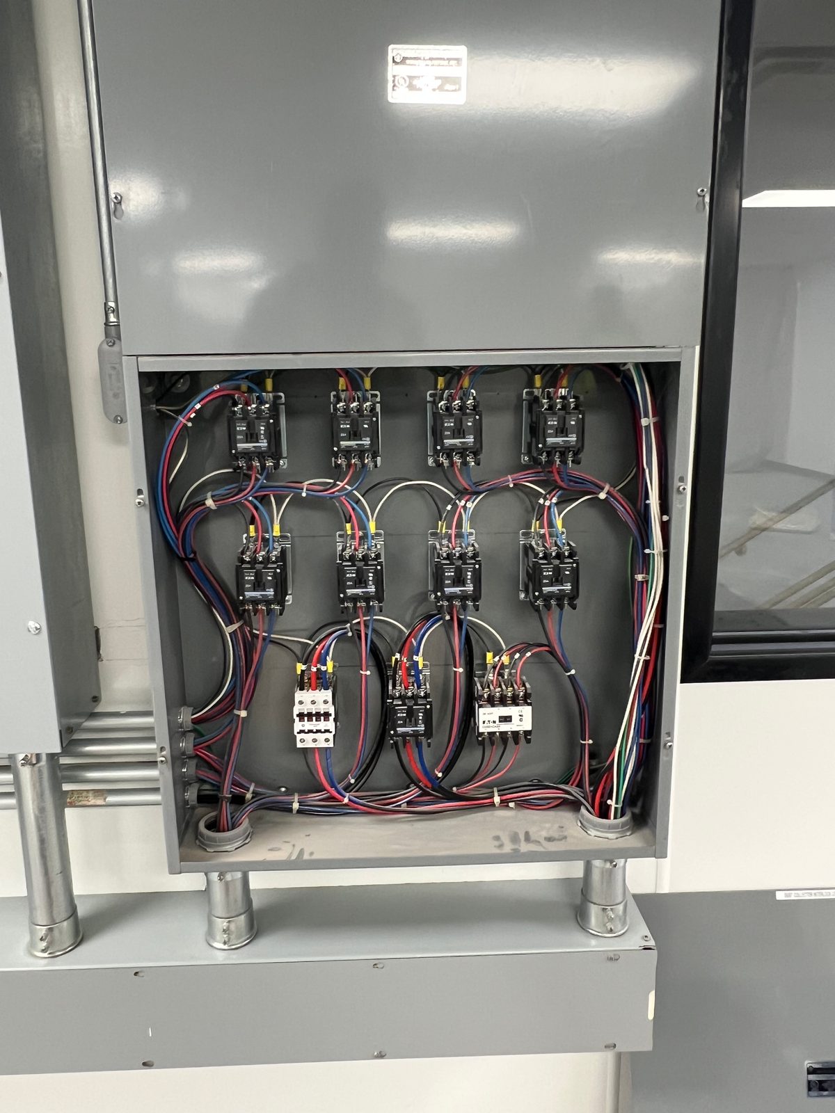 Enclosure with eight contactors and two relays wired in color-coded conductors, mounted above conduits