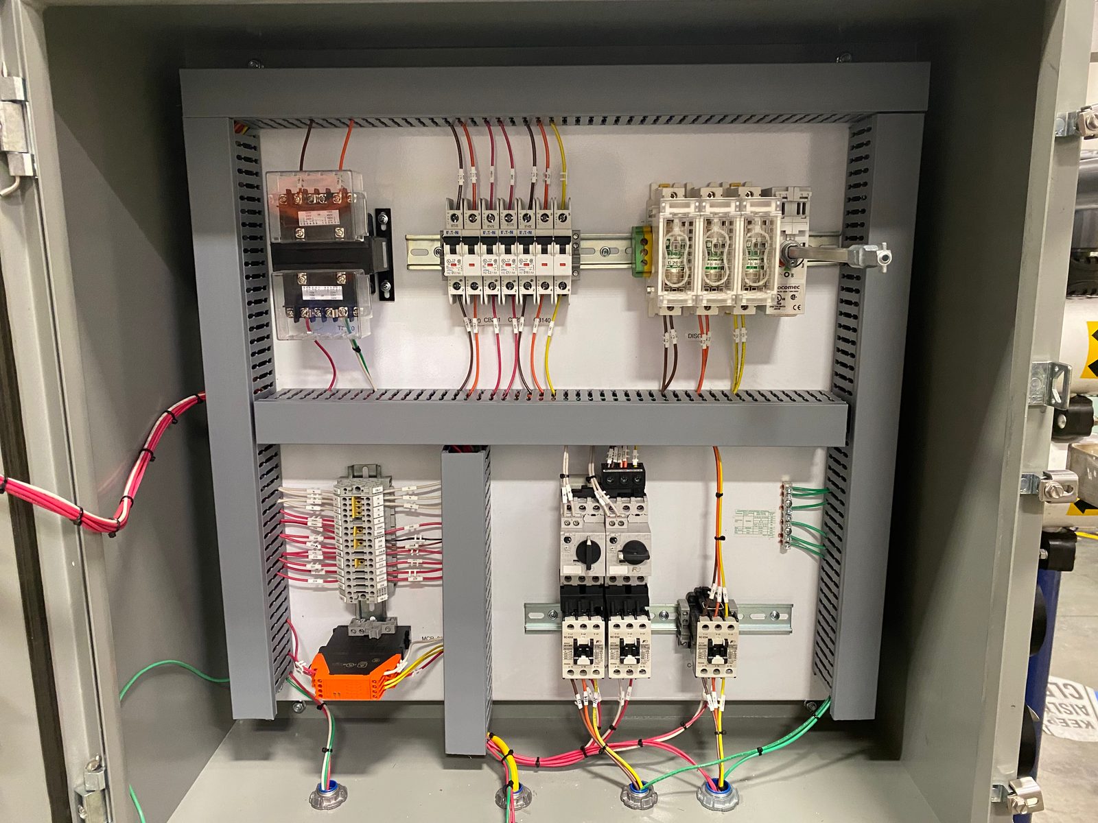 Industrial control panel on a white backplate with contactors, fuse holders, terminal blocks and motor protectors wired in neat runs