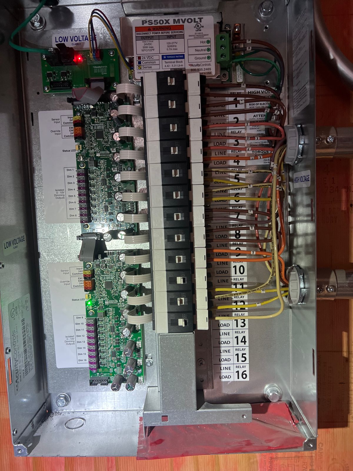 Lighting control relay panel with a control board on the left and a column of numbered relays wired with color-coded conductors