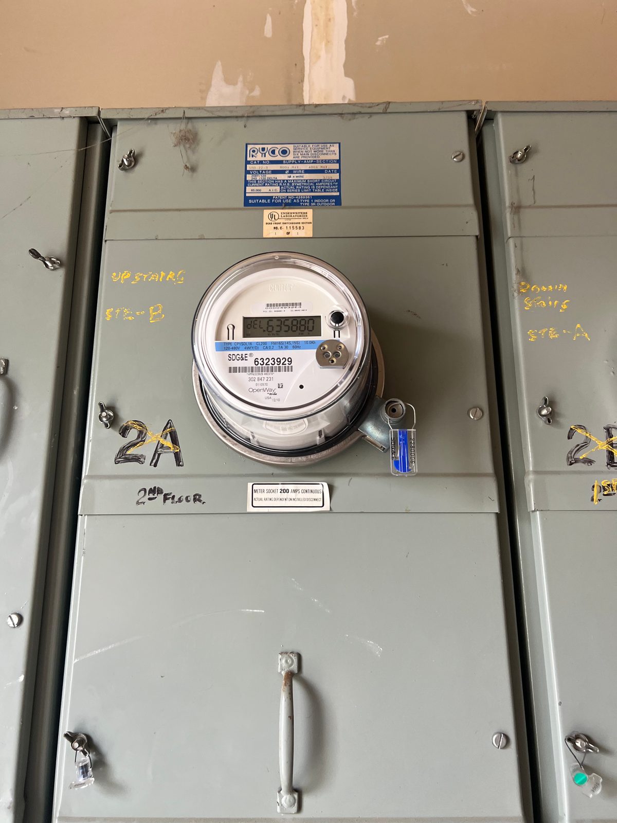 Close-up of a meter bank with a smart meter set in one position and unit and floor labels marked on each cover