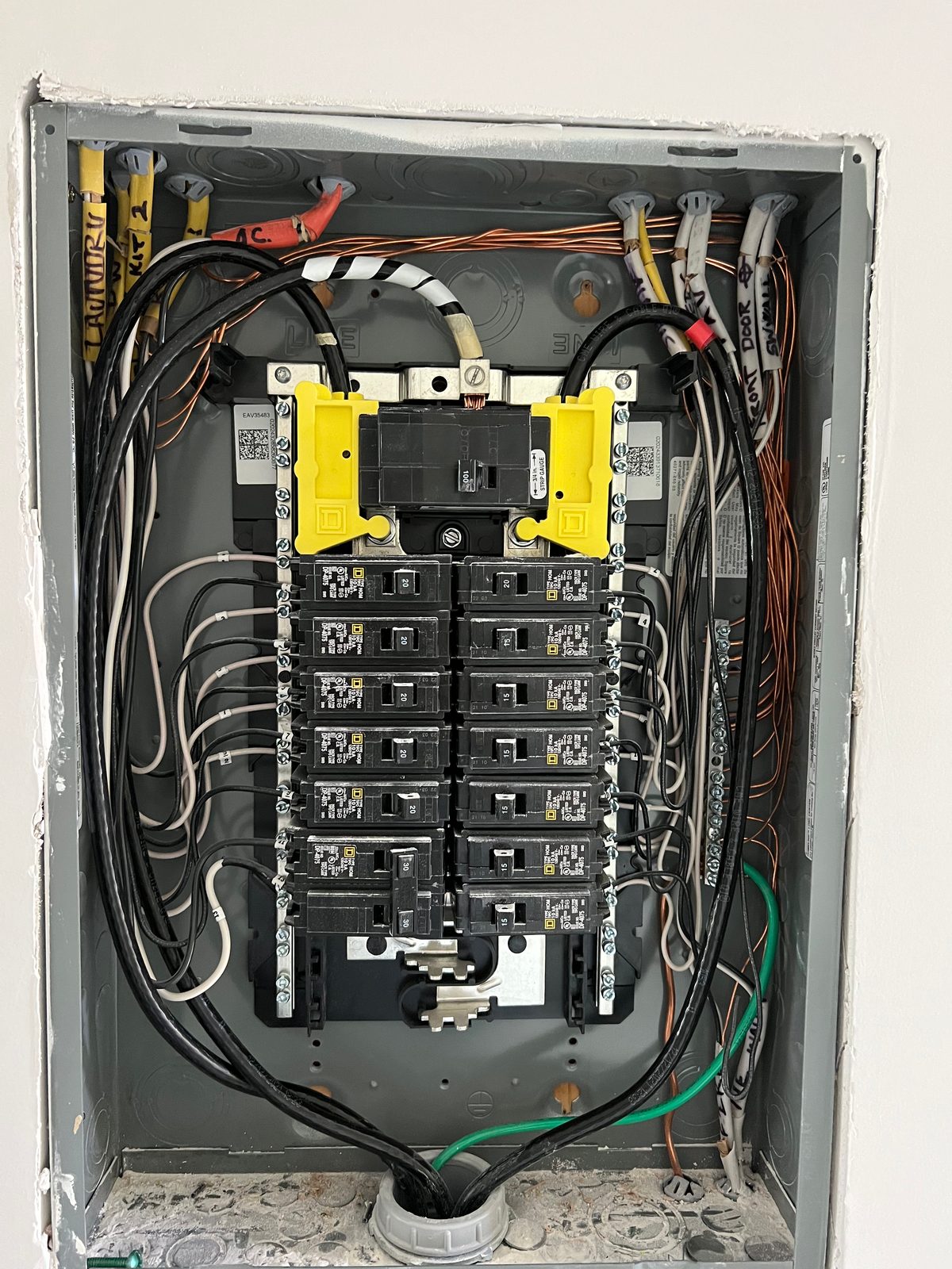New residential breaker panel with the cover off, cables formed neatly around both sides and landed on two columns of breakers